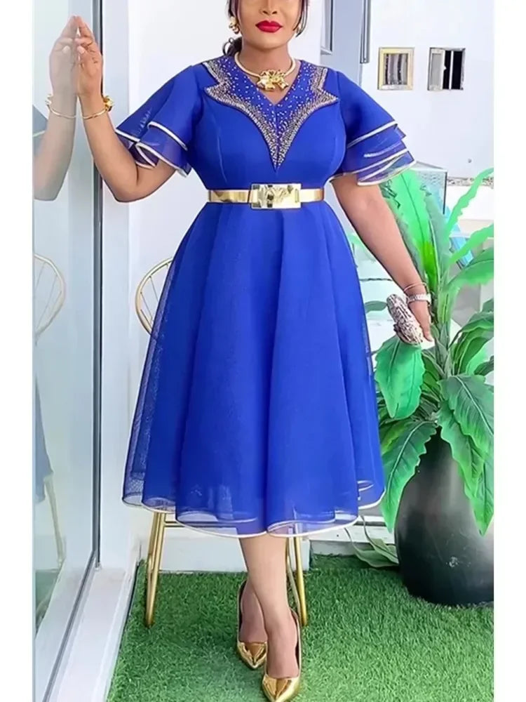 A woman wears a royal blue midi dress with a beaded V-neck, layered sleeves, and a gold belt.