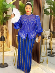 A woman wears a royal blue long-sleeved maxi dress with sequin floral patterns and striped details.