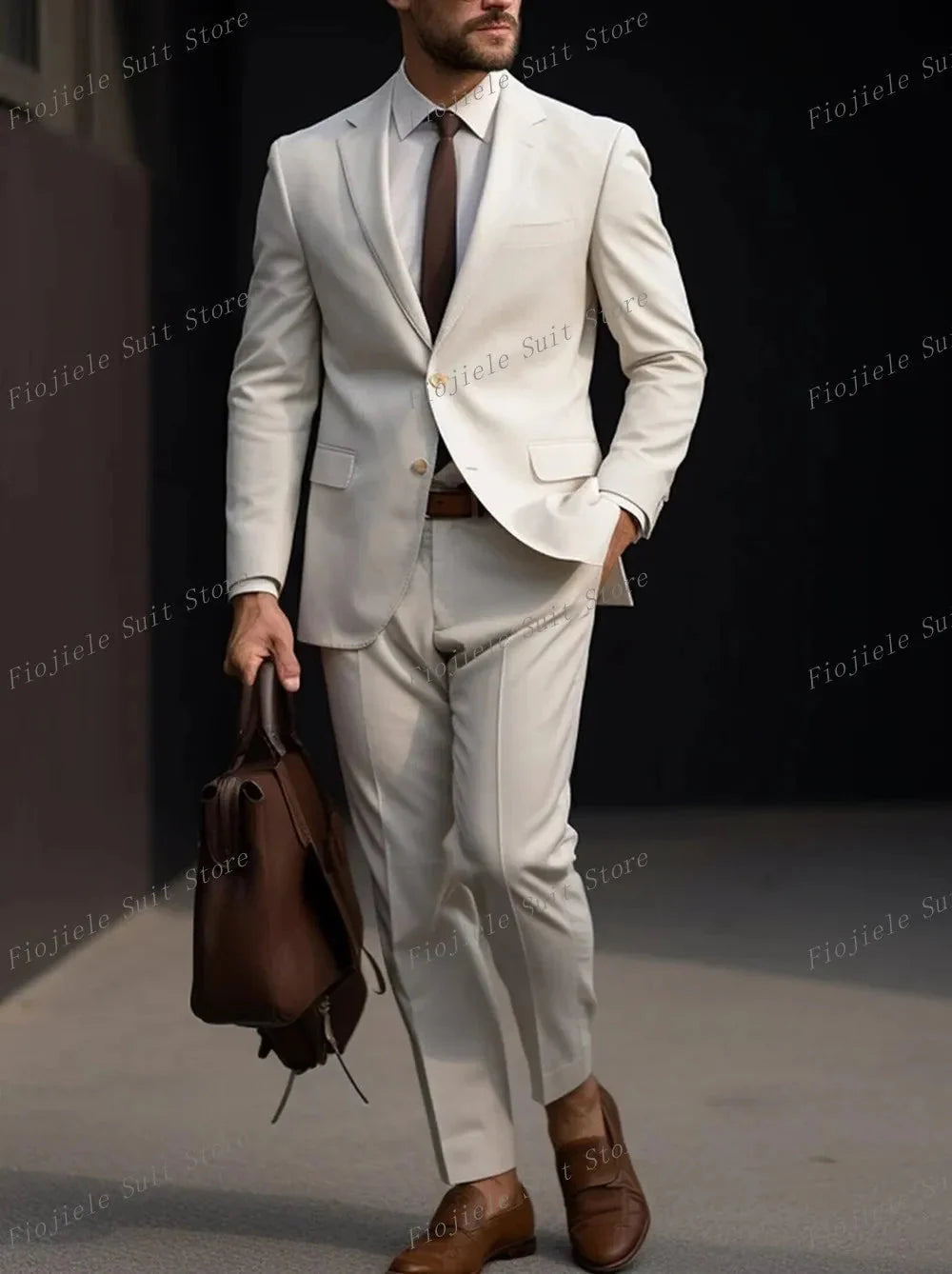A man wears a light beige two-piece suit with a brown tie, brown belt, and brown loafers.