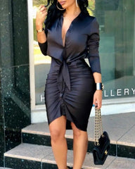 A woman wears a black long-sleeve bodycon dress with a deep V-neck and a front tie detail.