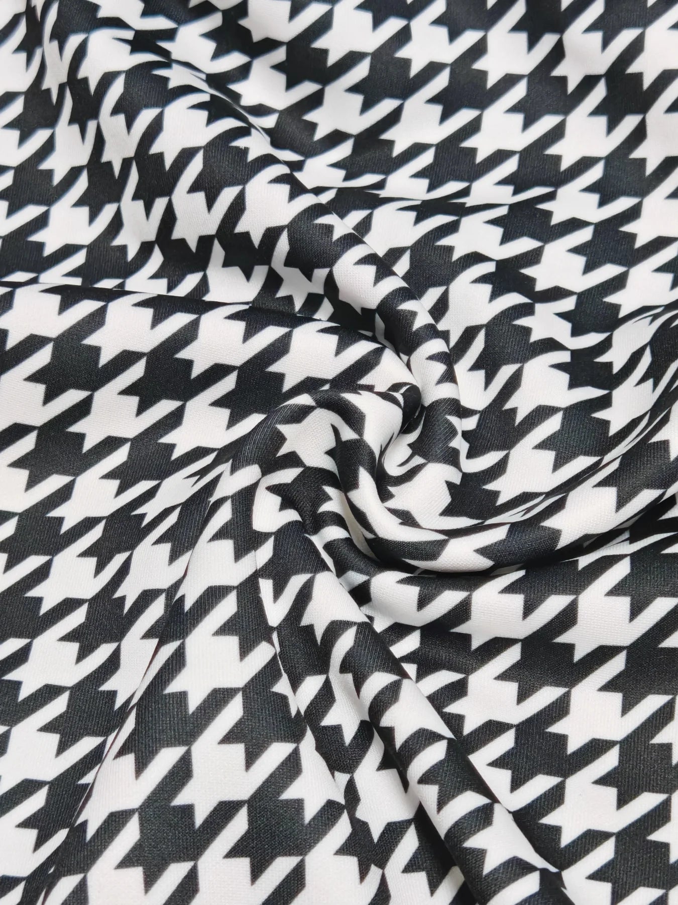 A close-up view of fabric featuring a classic black and white houndstooth pattern.
