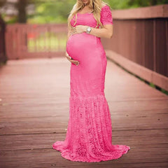 A pregnant woman wears a short-sleeved, ankle-length pink lace mermaid maternity dress.