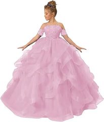 A girl wears a light pink off-shoulder ball gown with lace appliques and a ruffled tulle skirt.