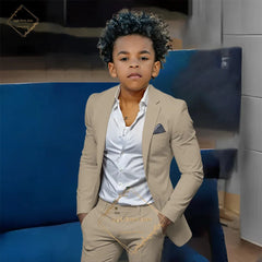 A young boy wears a slim-fit tan single-breasted suit jacket and matching trousers.