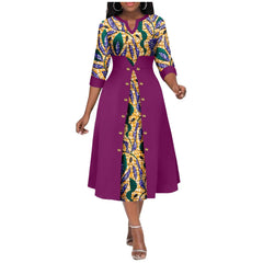 A woman wears a mid-calf V-neck dress featuring a purple overlay with buttons over a printed skirt.