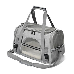 A grey soft-sided pet carrier with mesh windows, top handles, and a shoulder strap.
