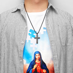 A person wears a black stainless steel cross pendant engraved with text on a matching link chain.