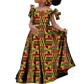 A girl wears a long, off-the-shoulder African print dress with bow sleeves and a matching headscarf.