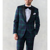 A man wears a slim-fit green and navy plaid two-piece tuxedo with a black peaked lapel.