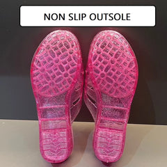 A pair of pink glittery transparent jelly slippers shown from the bottom to display the tread.