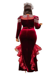 A woman wears a long-sleeved burgundy velvet mermaid gown with crystal embellishments and ruffles.