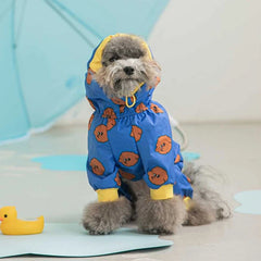 A small dog wearing a blue hooded raincoat with a brown cartoon pattern and yellow cuffs.