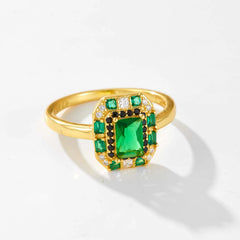 A gold-plated sterling silver ring featuring a large emerald-cut green zircon surrounded by smaller green, black, and clear stones.