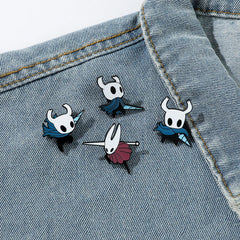 Four Hollow Knight enamel pins featuring the Knight and Hornet are pinned to a denim jacket.