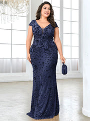 A plus-size woman wears a floor-length navy blue mermaid evening gown with sequin embellishments.