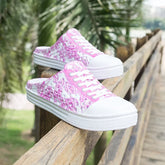 A pair of white slip-on sneakers with a pink floral pattern and white laces.