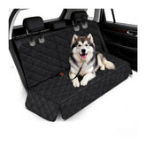 A black quilted waterproof dog car seat cover installed in the back seat with a husky sitting on it.