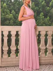 A pregnant woman wears a sleeveless, ankle-length dusty pink maternity dress with a V-neck.