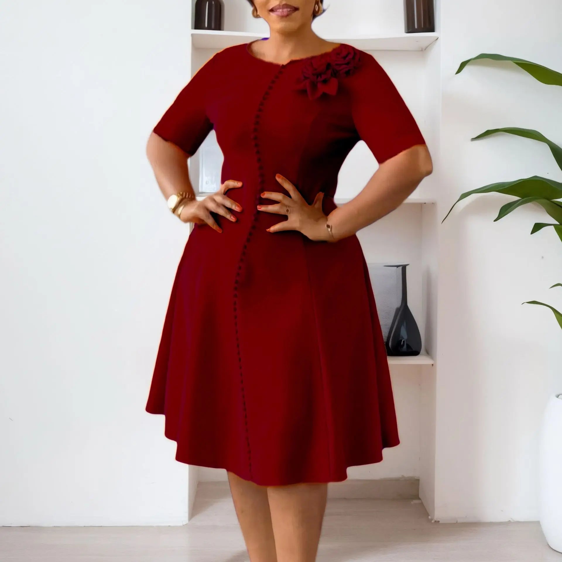 A woman wears a knee-length, burgundy A-line dress with short sleeves, a round neck, and buttons.