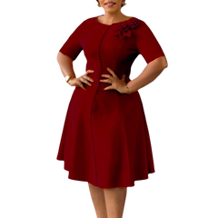 A woman wears a knee-length, burgundy A-line dress with short sleeves, a round neck, and buttons.