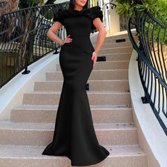 A woman wears a black floor-length mermaid gown with an off-the-shoulder ruffled neckline.