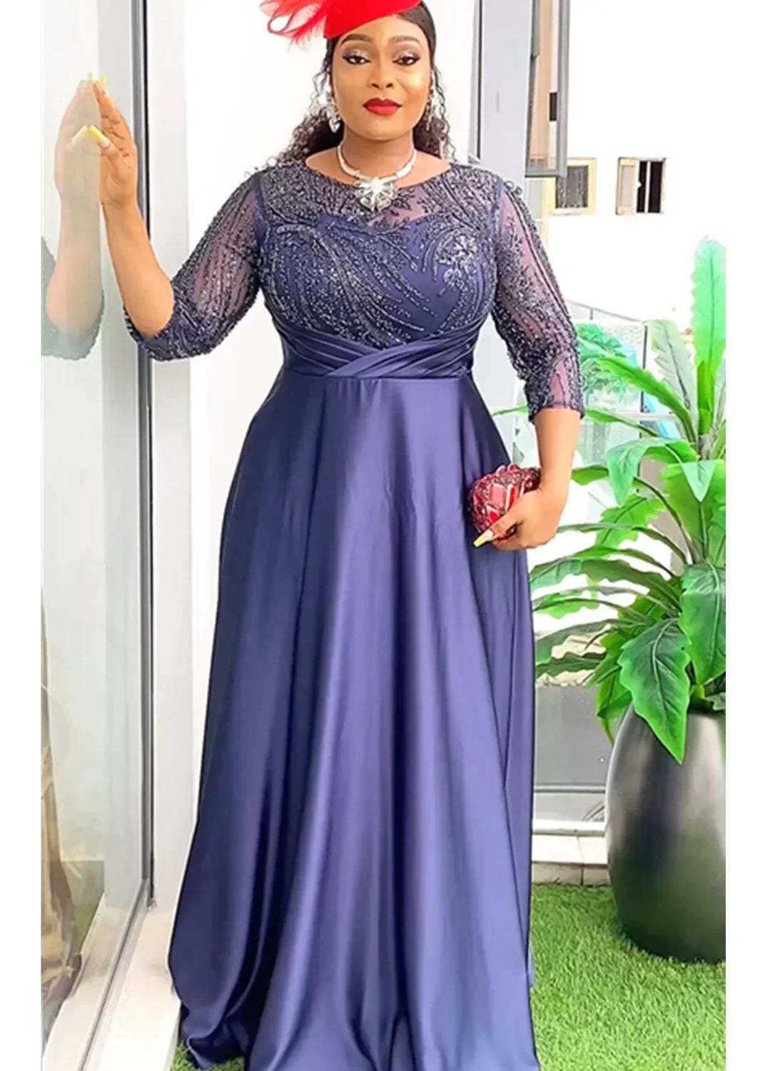 A woman wears a long-sleeved navy blue maxi dress with a sequined bodice and satin skirt.