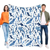 A man and a woman hold up a soft flannel blanket featuring a blue watercolor shark pattern.