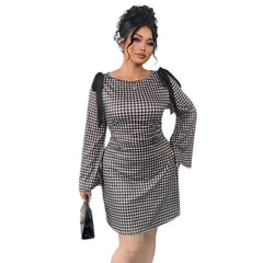 A woman wears a black and white plaid long-sleeved dress with knot details on the shoulders.