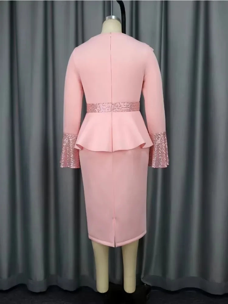 A pink midi dress with a peplum waist, long sleeves with sequined cuffs, and a back zipper.