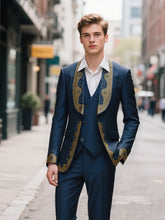 A man wears a navy blue three-piece suit featuring gold beaded lapel and cuff embellishments.