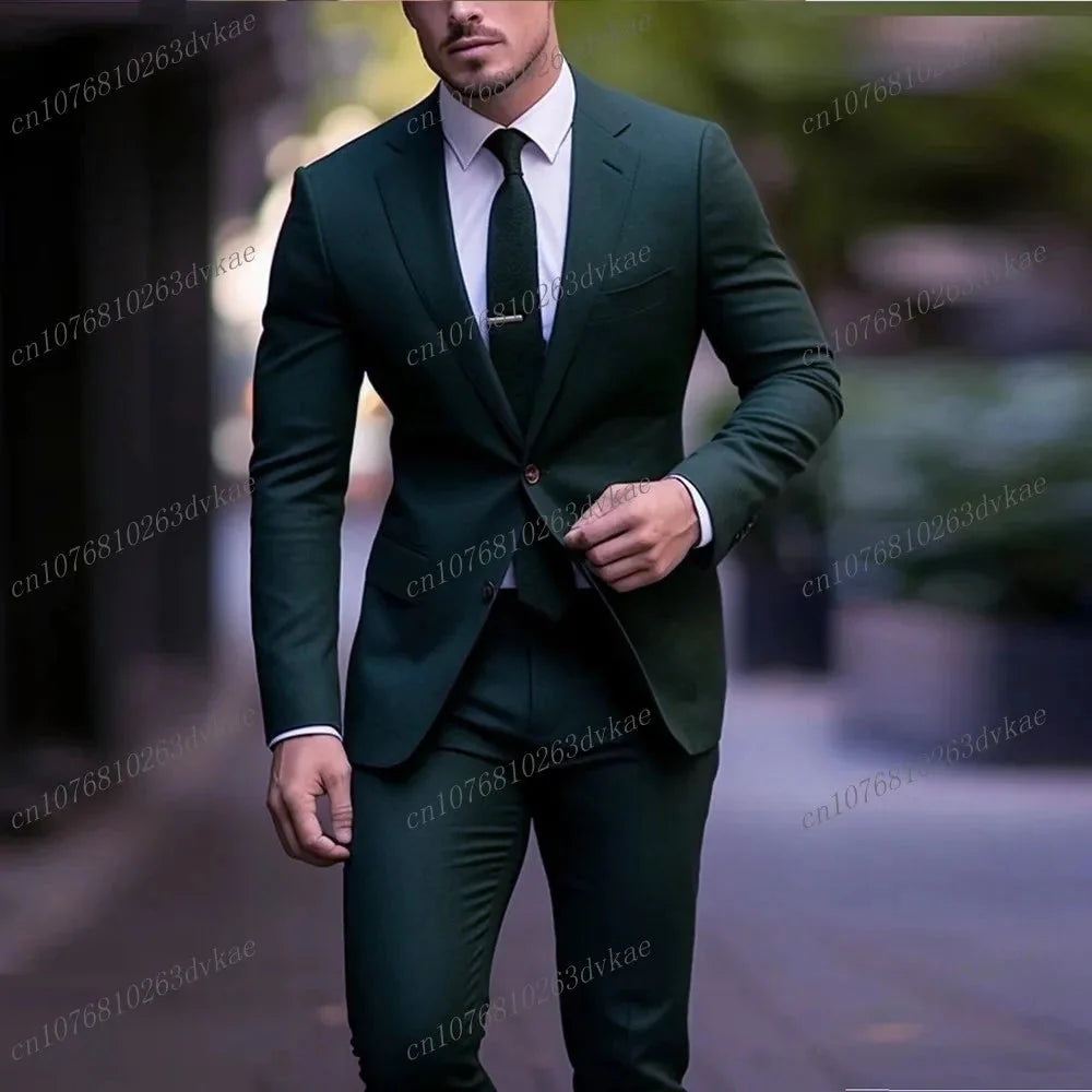 A man wears a dark green two-piece formal suit with a white shirt and a matching tie.