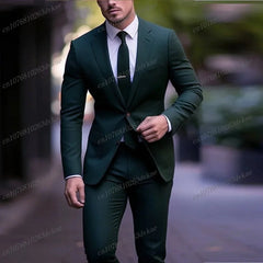 A man wears a dark green two-piece formal suit with a white shirt and a matching tie.