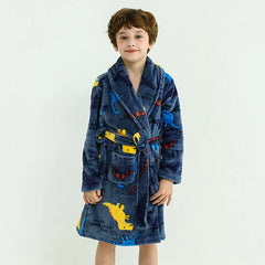 A child wears a blue flannel bathrobe featuring a colorful dinosaur pattern and a tie waist.