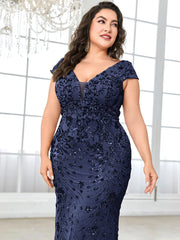 A plus-size woman wears a floor-length navy blue mermaid evening gown with sequin floral patterns.