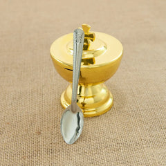 A golden communion cup with a cross-topped lid and a matching silver-toned spoon.