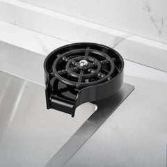 A black automatic glass cup rinser with a circular spray nozzle mounted on a kitchen sink.