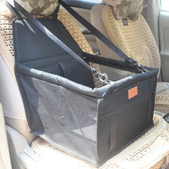 A black, foldable pet car seat with mesh sides and adjustable straps hanging from a headrest.
