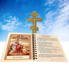 An open spiral-bound prayer book featuring the Crucifixion sits before a wooden crucifix.