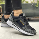 A pair of black and grey patterned wedge sneakers with gold accents and white soles.
