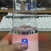 A hand holds a portable mini blender with a clear cup and a pink base.