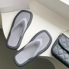 A pair of grey flip-flop sandals with a thick black border resting on a white surface.