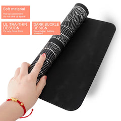 A hand holds a flexible, black, rollable foot massage mat with a patterned surface.