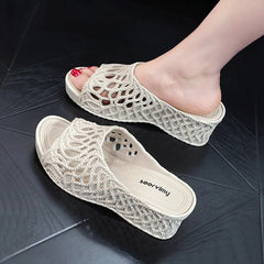 A pair of beige wedge slippers with a hollow-out rope design and a peep-toe front.