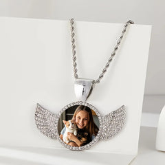 A silver round pendant necklace featuring angel wings and a custom photo of a girl with two cats.