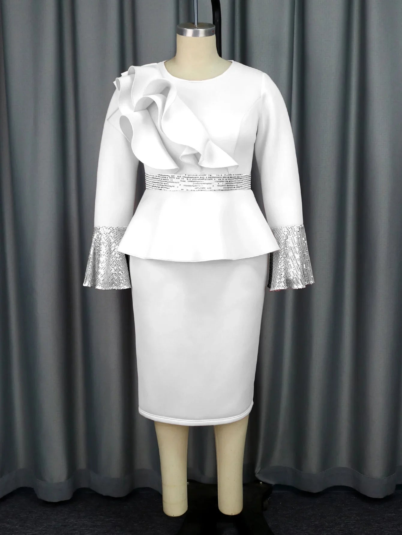 A white knee-length sheath dress with a ruffled shoulder, sequined waist, and flared cuffs.