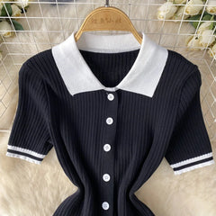 A black short-sleeved knit polo shirt with a white collar and striped sleeve cuffs.