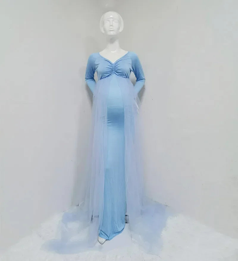 A light blue maternity dress with long sleeves, a V-neck, and a sheer tulle cape with a long train.