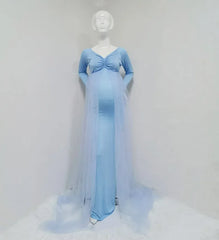 A light blue maternity dress with long sleeves, a V-neck, and a sheer tulle cape with a long train.