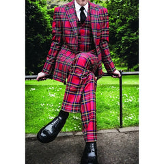 A man wears a three-piece red plaid suit with a white shirt and black tie.