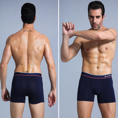 A man wearing navy blue cotton boxer shorts with a branded elastic waistband.